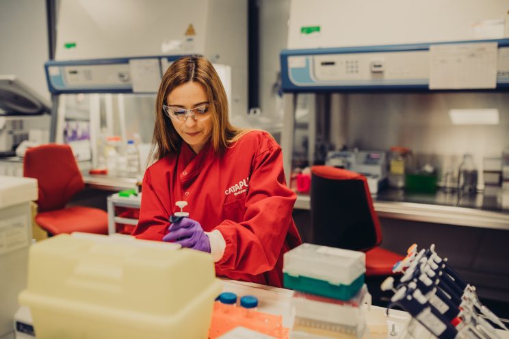 Scientist in a red lab coat working on a bench