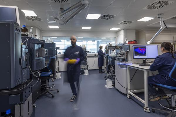 A photograph of a mass spectrometry laboratory with scientists working between machines