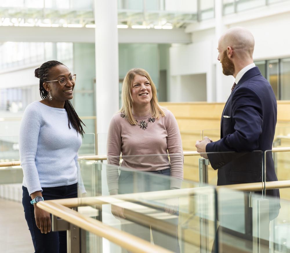 Three people engaged in conversation indoors.