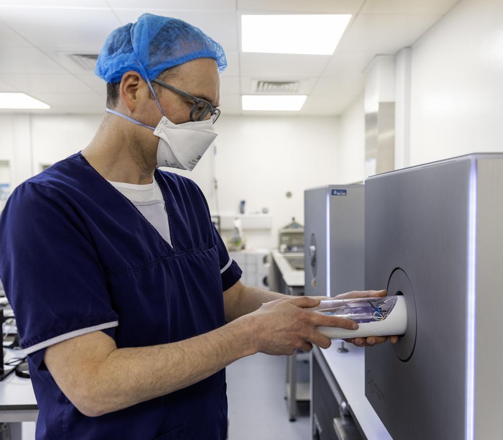 A scientist putting tracers into a drug discovery machine in a laboratory.