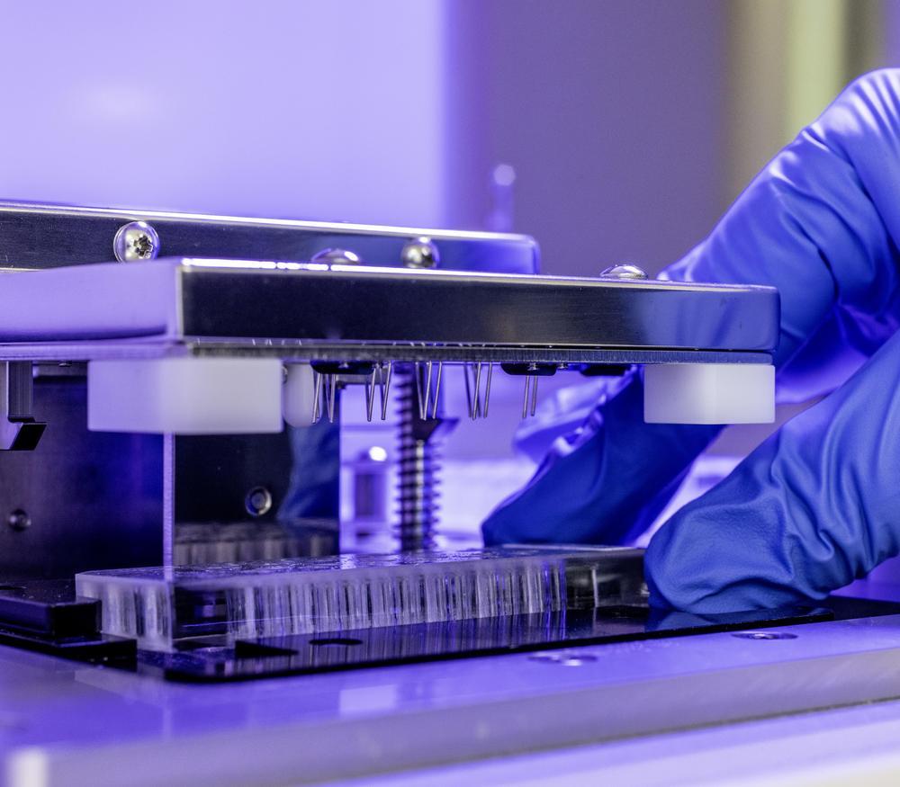 A scientist with gloves using a Nanostring nCounter prep station.
